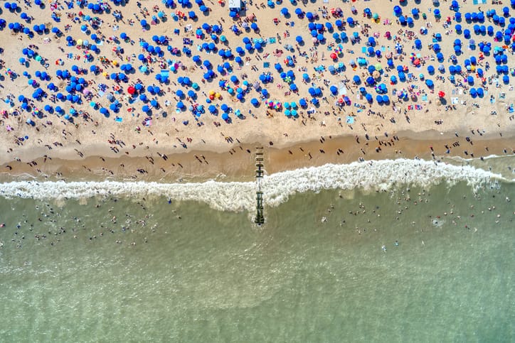 A scenic aerial of Rehoboth Beach featuring the iconic boardwalk, sandy shoreline, and Atlantic Ocean waves along Delaware’s coast